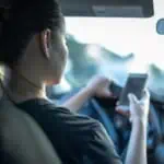 Driver is uing her phone, not payint attention to roads